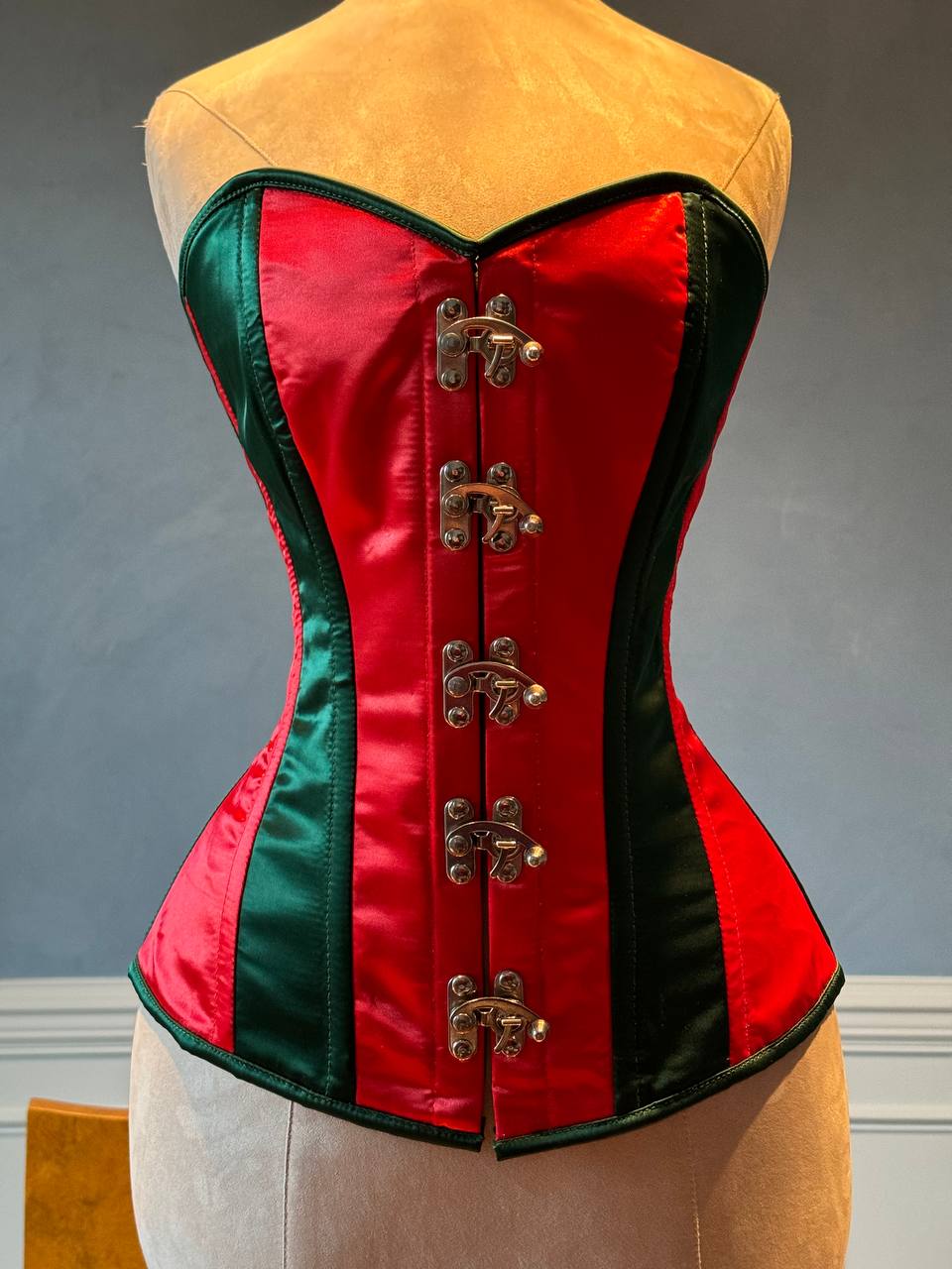 
                  
                    Corset overbust rosso e verde in stile Santa con chiusure steampunk davanti in raso. Il corsetto è realizzato personalmente secondo le tue misure.
                  
                
