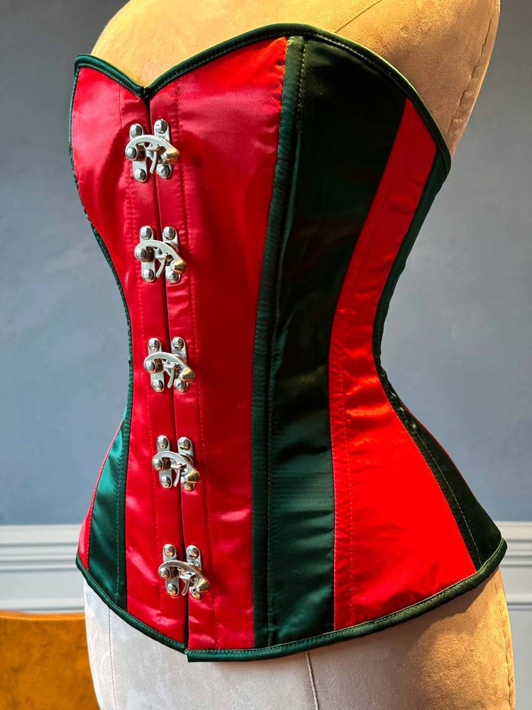 
                  
                    Corset overbust rosso e verde in stile Santa con chiusure steampunk davanti in raso. Il corsetto è realizzato personalmente secondo le tue misure.
                  
                
