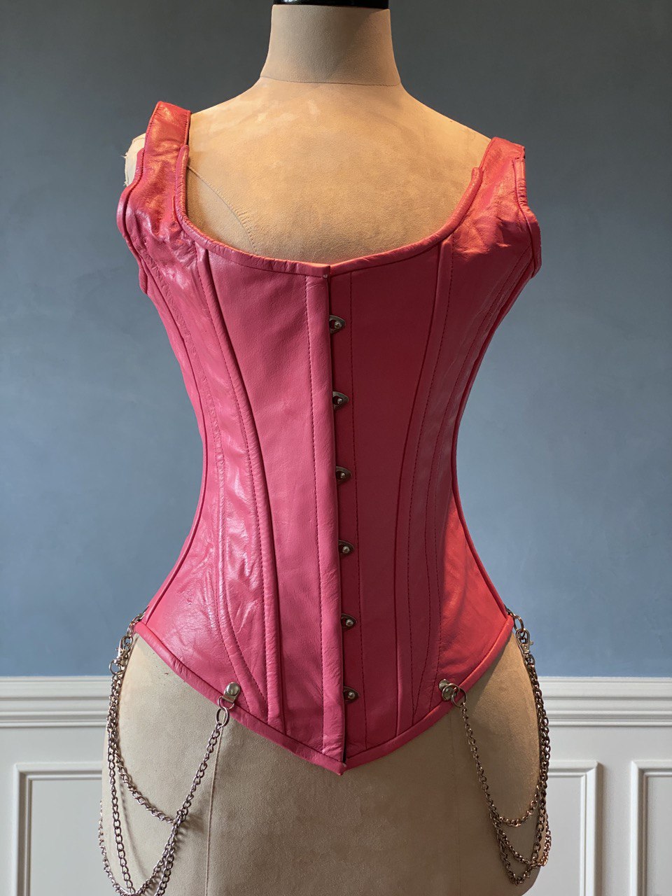 Salmon color leather corset vest with shoulder straps and chains. Steel-boned corset top for tight lacing. Corsettery