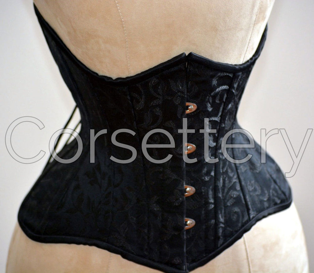 Double row steel boned underbust corset of short design with long hips made of brocade. Corsettery