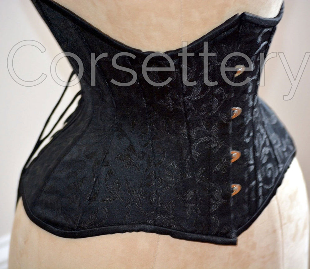 Double row steel boned underbust corset of short design with long hips made of brocade.