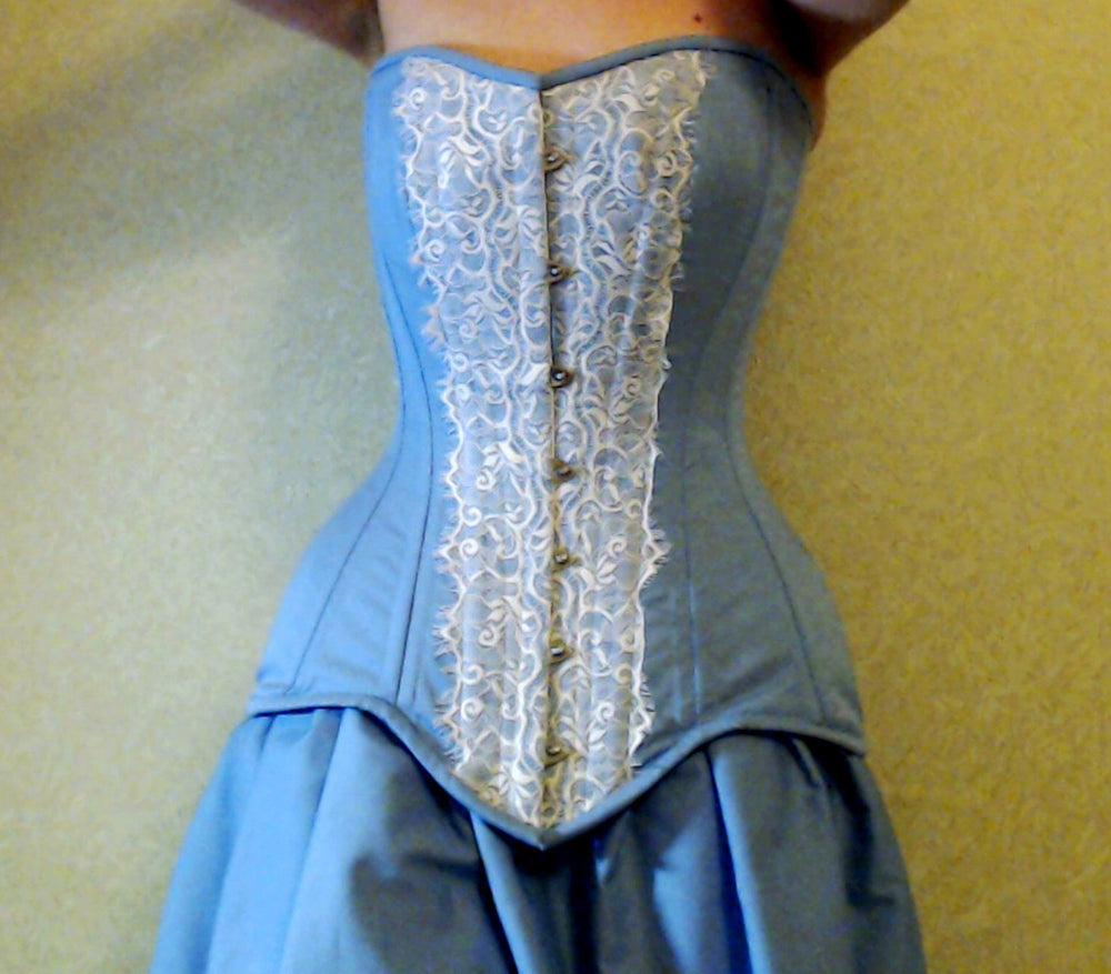 Corset sablier en acier désossé bleu clair pour un laçage serré recouvert de lacets de chantilly. Collection de corseterie accro à la dentelle.